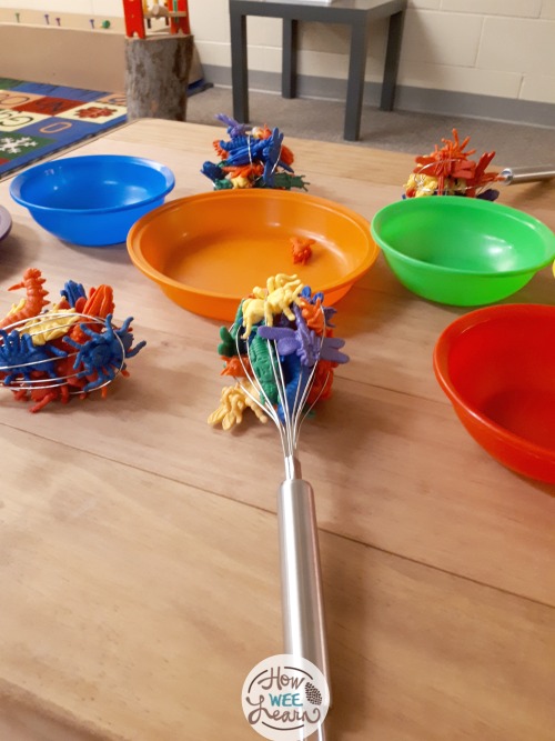 a whisk with plastic animals stuck inside for preschool fine motor play