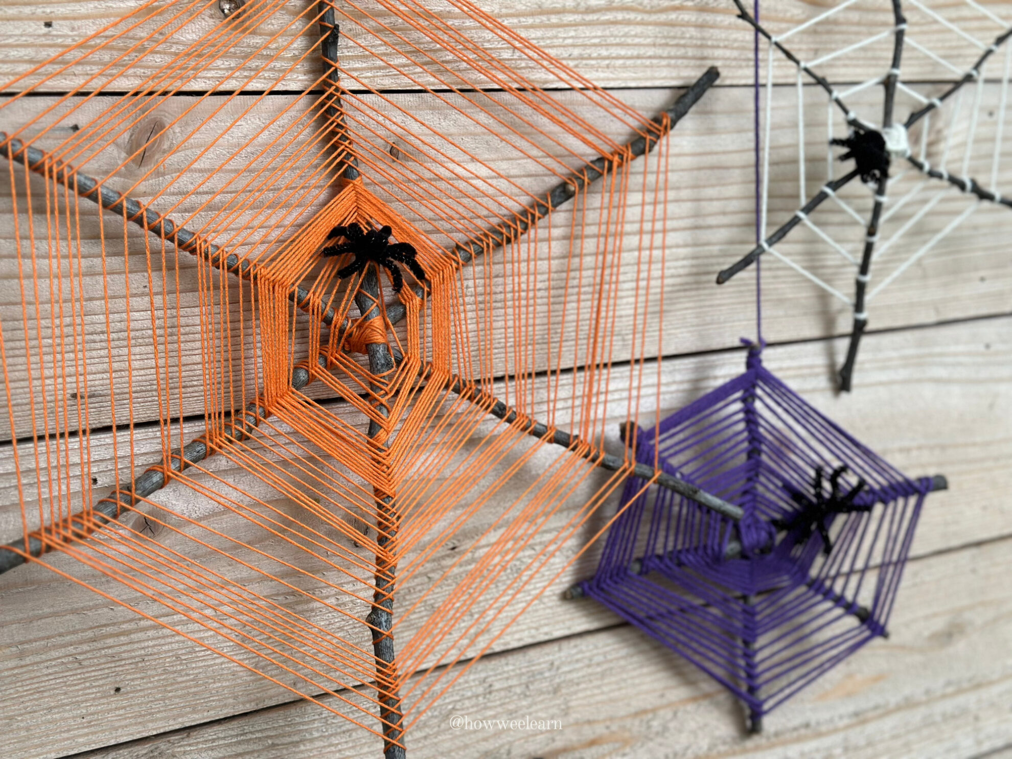 Orange, purple, and white spider web weavings on sticks